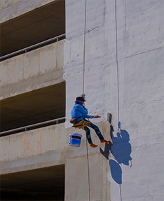 Técnico especializado realizando pintura de fachada en altura
