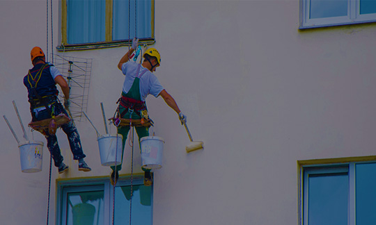 Aplicación de pintura en fachada de edificio a gran altura